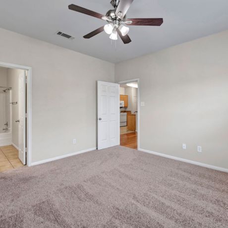 Riviera Apartments in Waco, TX with spacious, carpeted bedroom, ceiling fan, and en suite bathroom with bathtub