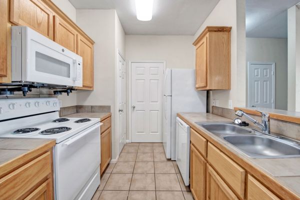 Riviera Apartments in Waco, TX with large kitchen, abundant cabinet storage, dishwasher, refrigerator, microwave, and large tile flooring