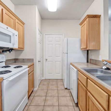 Riviera Apartments in Waco, TX with large kitchen, abundant cabinet storage, dishwasher, refrigerator, microwave, and large tile flooring